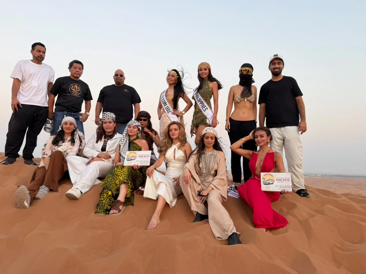 Group of desert safari travelers posing together on the sand dunes