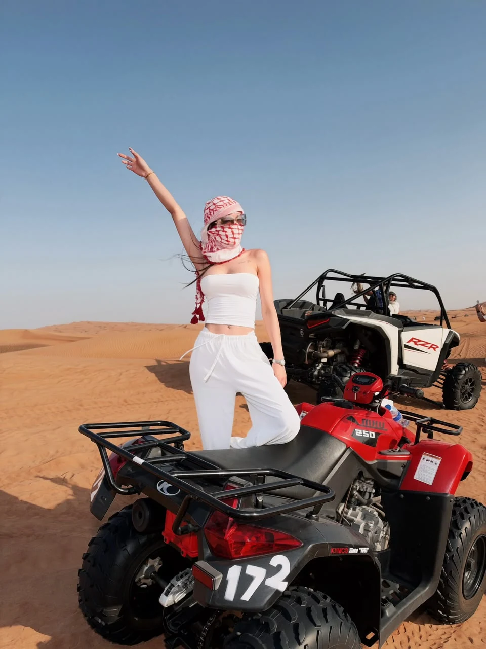 Woman posing next to a quad bike in the Dubai desert