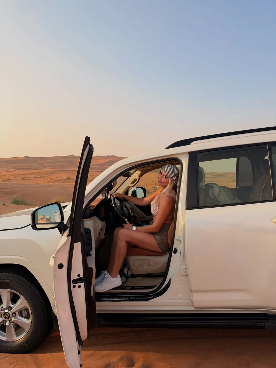 Visitor stepping into a white 4x4 vehicle during a desert safari