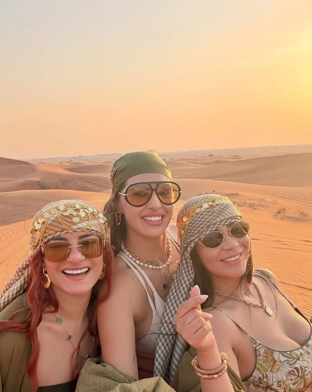 Three friends taking a selfie on the desert dunes at sunset